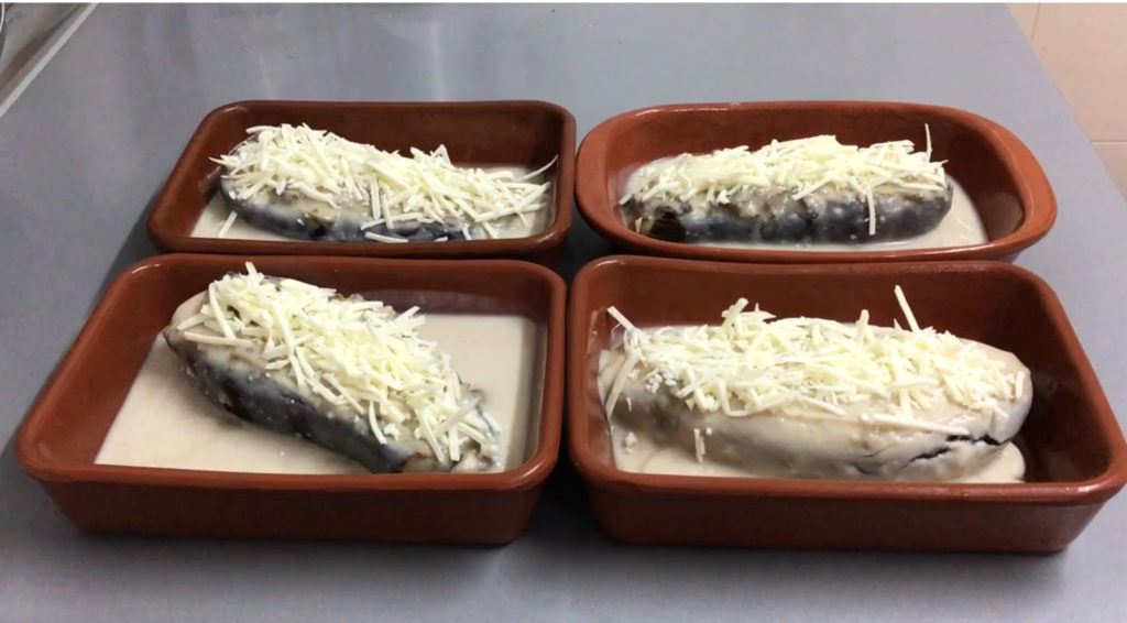 Imagen de 4 bandejitas con las berenjenas rellenas de setas listas para ser gratinadas.