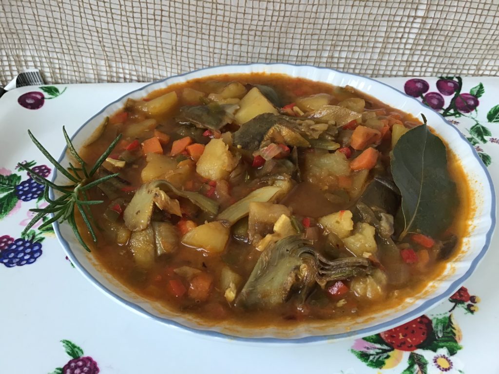 Un plato rebosante de estofado, con una pina deliciosa. Se aprecian los trozos de alcachofa, de zanahoria y de patata.