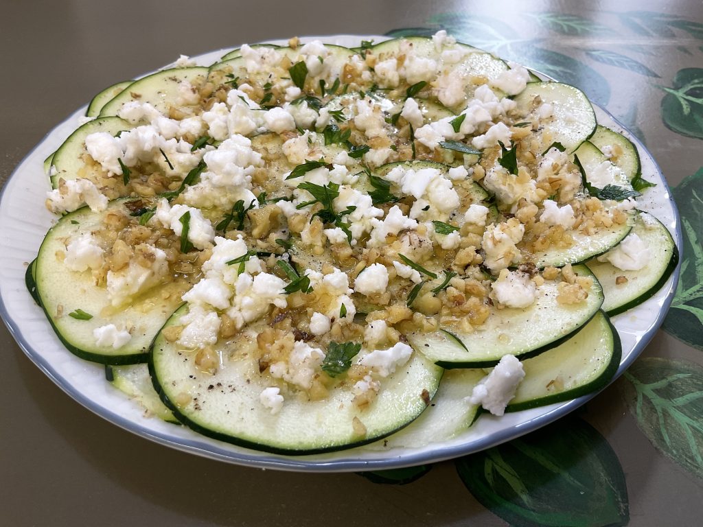 Superplato de carpaccio de calabacín con nueces y queso vegetal estilo feta, la imagen refleja la presentación deseada, poniendo los ingredientes por capas.