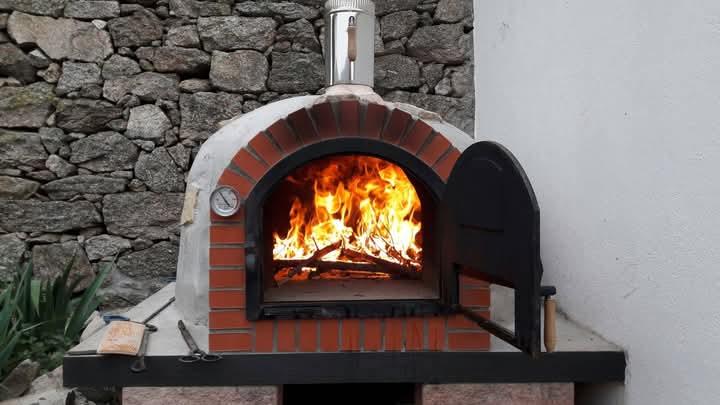 Horno de leña actual, de fabricación casera, de ladrillos y mortero refractario, y con termostato incorporado para mejor control de la temperatura.